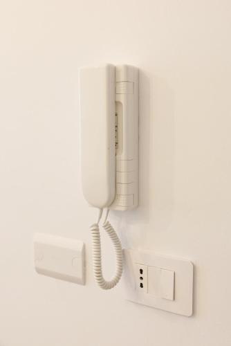 a white phone is hanging on a wall at Casa Afrodite Bilocale con Sauna e Vasca Privata in Perosa Argentina