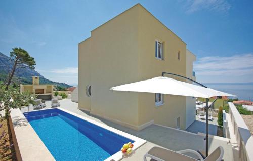 a swimming pool with an umbrella next to a house at Lux Apartments in Makarska