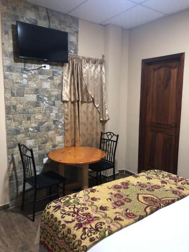 a bedroom with a bed and a table and a tv at Hotel Guest House Inn in San Pedro Sula