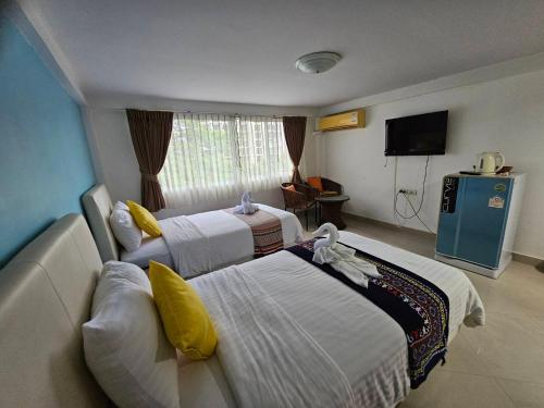 a hotel room with two beds and a television at Hello Jomtien in Jomtien Beach