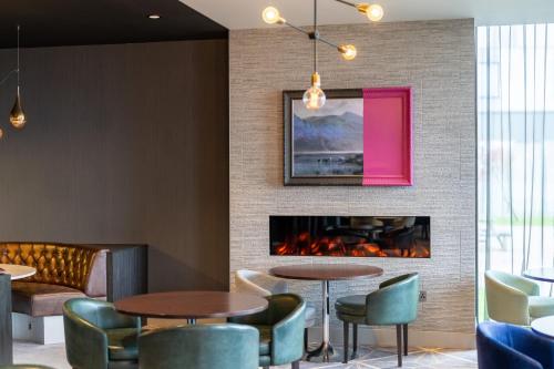 a lobby with tables and chairs and a fireplace at Crowne Plaza Aberdeen Airport by IHG in Dyce