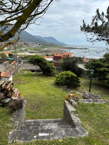 a stone stairway leading to a field with the ocean at A casa do Cabezo in Mougás