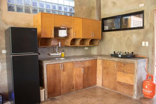a kitchen with wooden cabinets and a black refrigerator at Ohayo Siargao in General Luna