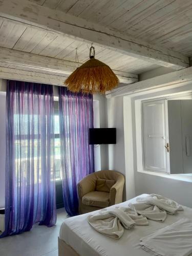 a bedroom with a bed and a chair and a window at August Elafonisos in Elafonisos