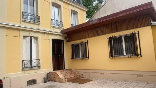 a yellow building with a door and windows at Votre Maison Lointaine in Pantin