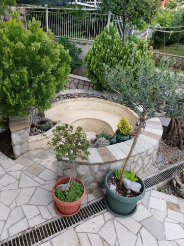 a garden with three potted trees in pots at Kerch Apartments in Radovići