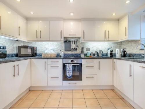 a white kitchen with white cabinets and appliances at Costal Retreat with Garden & BBQ in Lymington