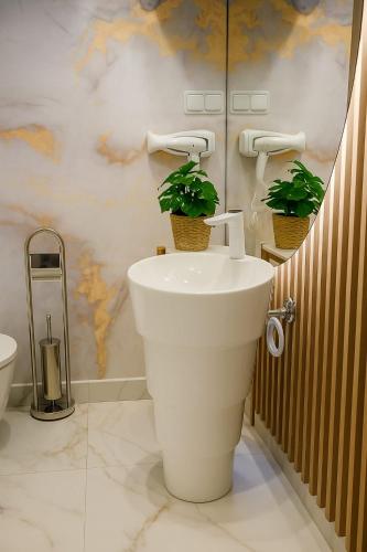 a bathroom with a white sink and two potted plants at Vila AMAZON in Dubova