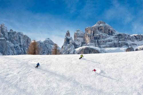 three people skiing down a snow covered mountain at Hotel Plan Murin in La Valle