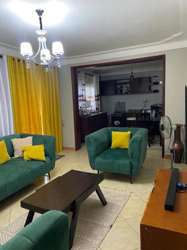 a living room with two green couches and a table at Ambassador residence in Kampala