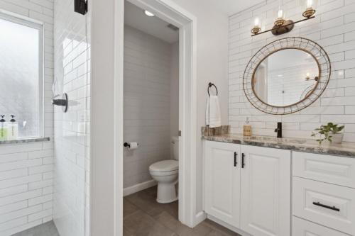 a white bathroom with a toilet and a mirror at NEW Reins & Rivets by PaseoHomesAZ - Heated Pool in Tempe