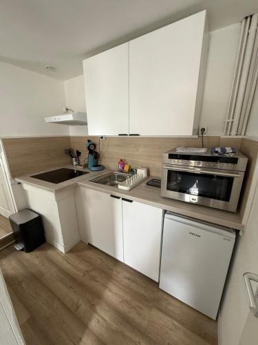 une petite cuisine avec des armoires blanches et un évier dans l'établissement Maison de ville cosy pour 4 personnes, à Grand-Couronne