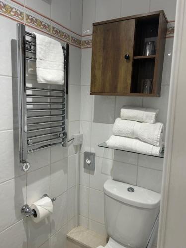 a bathroom with a toilet and a cabinet with towels at Melbourne Guest House in Bowness-on-Windermere