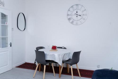 a dining room with a table and chairs and a clock at Spacious Pad - Long Stays & Contractors - Close to Sports Village, Leigh Market, & Mesnes Park - Easy Parking - Speedy Wi-Fi in Leigh