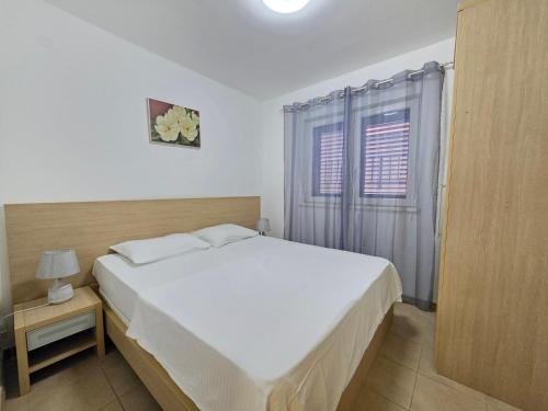 a bedroom with a white bed and a window at Blue Dream Apartment in Rafailovici