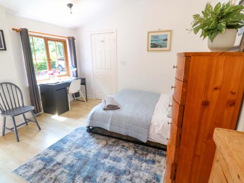 Un dormitorio con una cama, un escritorio y una mesa. en The Cow Shed, en Truro
