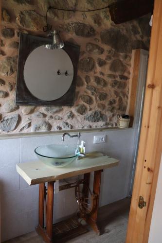 Łazienka z umywalką i lustrem na kamiennej ścianie w obiekcie Les Magranes Bed & Breakfast w mieście Argelaguer