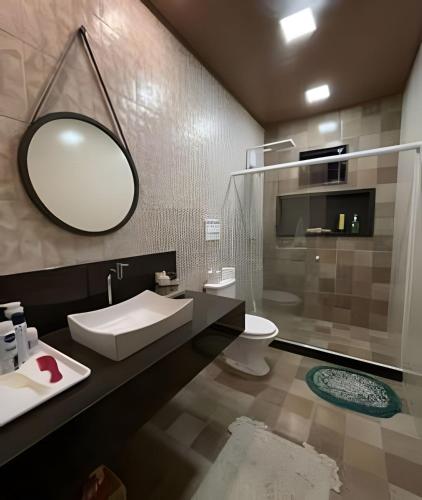 a bathroom with a sink and a mirror and a toilet at Sítio das Flores, 7 Km do centro de Castelo in Estancia do Castello