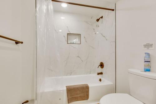 a white bathroom with a tub and a toilet at Vacation Launch Pad - Great for Groups in Arvada