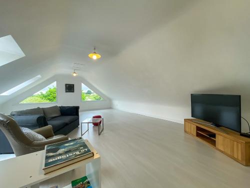 un salon avec un canapé et une télévision à écran plat dans l'établissement Maison Ty Losquet, à Plouha