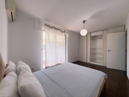 a white bedroom with a large bed and a window at Luxury 4 bedroom with 3 bathroom Cascais Lisbon walking distance to beach in Cascais
