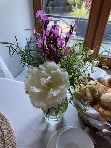 a vase filled with white and purple flowers on a table at Le Moulin des Farges in Meymac