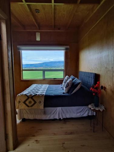 a bedroom with a bed with a large window at Vista al Paine - Refugio de Aventura in Torres del Paine