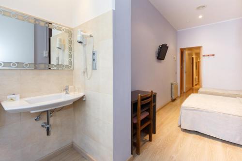 a bathroom with a sink and a bed in a room at Ciudad Condal Hostal - Paseo de Gracia in Barcelona