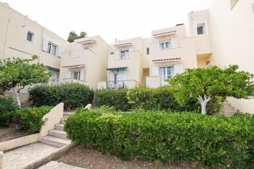 an apartment building with bushes in front of it at The White Rose Hotel in Poros