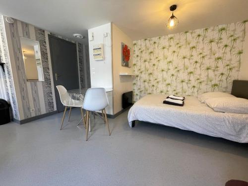 une chambre avec un lit, une table et des chaises dans l'établissement Studio au cœur de Lannion, à Lannion