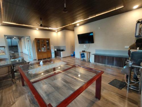 a large room with a glass table and a flat screen tv at Tropica Retreat by Dazzle Destinations - Private Waterfalls, Private Rooms and Bonfire in Aldūr
