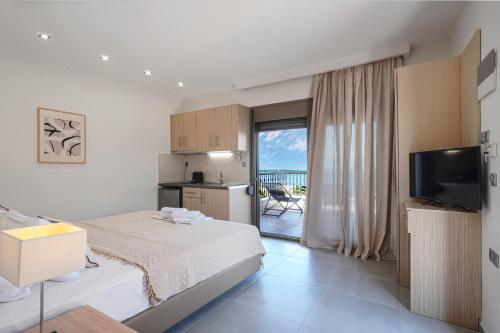 a bedroom with a bed and a television and a balcony at Panorama Dream Studios B in Vourvourou