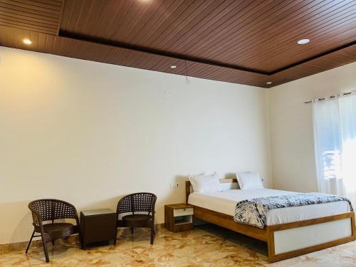 a bedroom with a bed and two chairs at Tropica Retreat by Dazzle Destinations - Private Waterfalls, Private Rooms and Bonfire in Aldūr