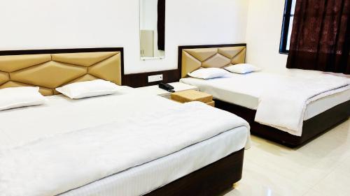 a bedroom with two beds with white sheets at Hotel Shree Rameshwaram in Godarpura