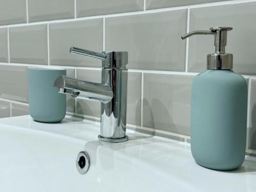 a bathroom sink with a soap dispenser next to a faucet at Abstract Escape! Stylish Apartment, Free Parking, 5 Minutes from Beach in Bournemouth