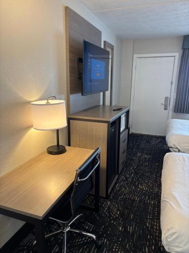 a hotel room with a desk with a bed and a tv at Baymont by Wyndham Petoskey in Petoskey