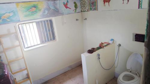 a bathroom with a toilet and a window at Vyugen Villa #01 in Kāraikkudi