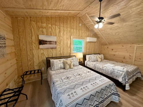 two beds in a room with wooden walls at Boulder Ridge Cabin in Eckerty