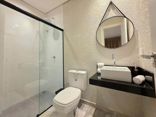 a bathroom with a toilet and a sink and a mirror at Studio Novo no Centro para 4 pessoas in Foz do Iguaçu