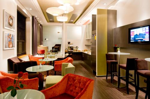 a restaurant with orange chairs and tables and a tv at Leonardo City Tower Hotel Tel Aviv in Tel Aviv