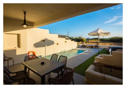 a patio with a table and chairs and a pool at Hidden Eden Residences - Private Pools in Plaka