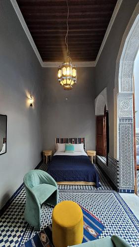 a bedroom with a bed and a chair and a chandelier at Riad Dar Bahija Fes in Fès