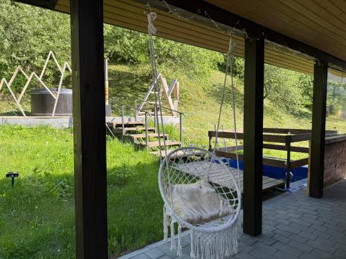 a porch with a swing and a playground with benches at Holiday Home Near FOREST in Skhidnitsa
