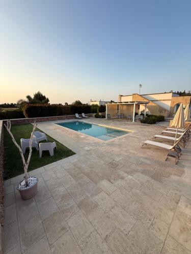 een achtertuin met een zwembad en een patio bij Villa Malepè con piscina in Torre dell'Orso
