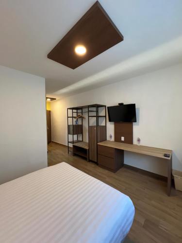 a room with a bed and a desk with a television at Hotel Mamá Dolores in Dolores Hidalgo