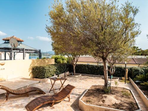 a patio with two benches and a tree at Casa Olivia - Casa indipendente nel centro di Cannigione a 3 minuti a piedi dal lungomare, 5 minuti a piedi dalla spiaggia più vicina e vicinissima alle spiagge più belle della Costa Smeralda in Cannigione