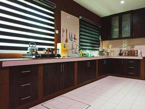 a kitchen with wooden cabinets and a counter top at Ipoh Tambun pool villa 5br 18pax bbq mahjong in Tambun