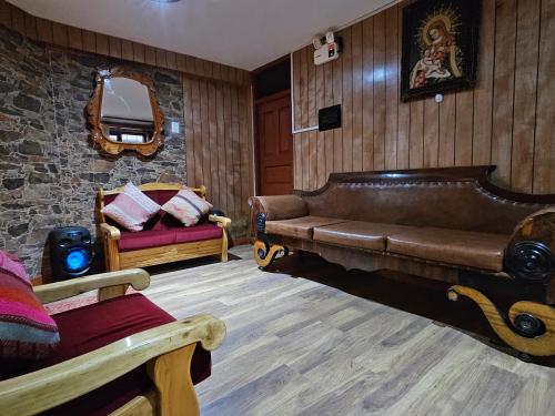 a living room with a leather couch and a chair at SAMAY WASI b&b in Cusco