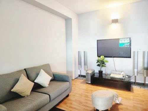 a living room with a couch and a flat screen tv at Ipoh Tambun pool villa 5br 18pax bbq mahjong in Tambun