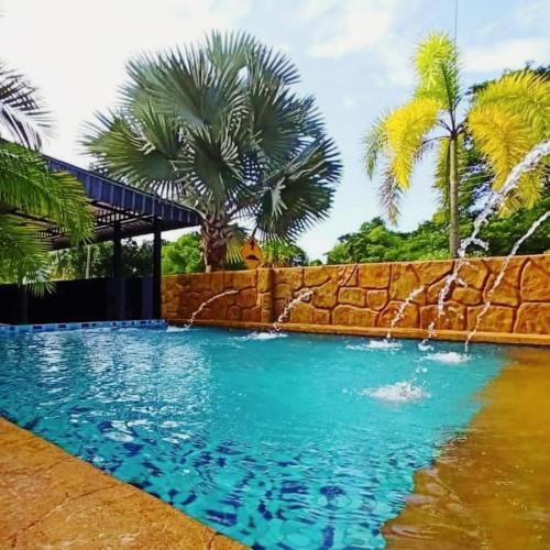 a swimming pool with a retaining wall and palm trees at Ipoh Tambun pool villa 5br 18pax bbq mahjong in Tambun